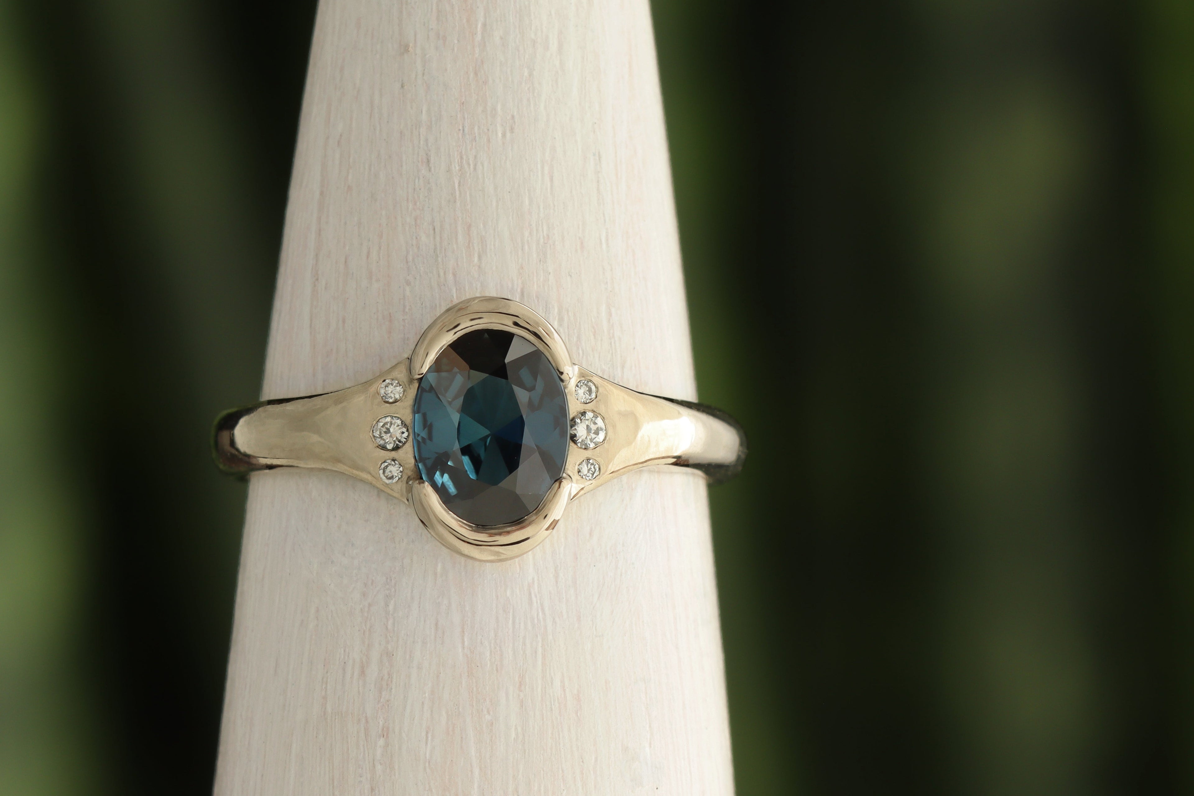 gold ring with half bezel teal australian sapphire and three small side diamonds.