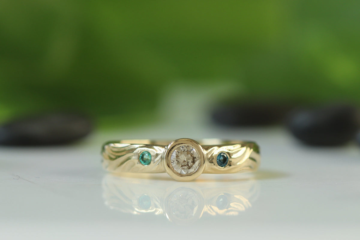 gold ring with carved organic texture. bezel set diamond and london blue topaz and emerald