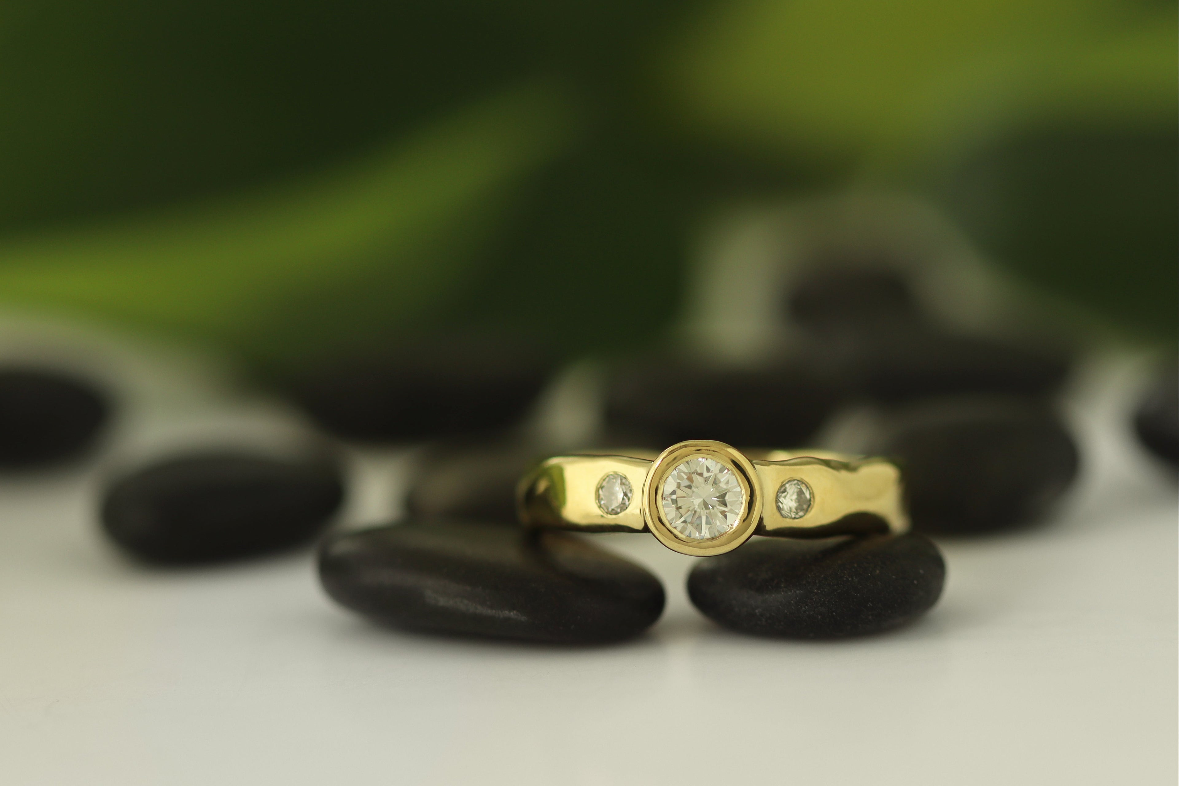 gold organic band with bezel set center diamond and two small side flush set diamonds